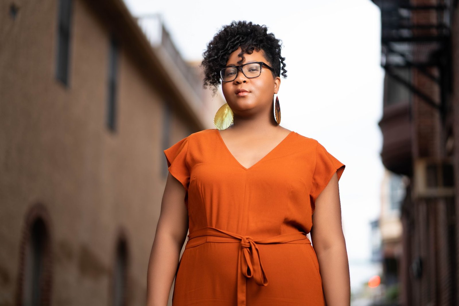 Donielle Houston standing in a brick alley, rust dress